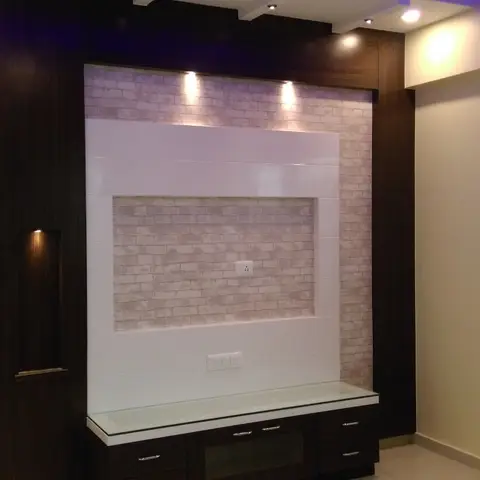 Living room TV feature wall in a dark wood frame with a cream brick-effect tile inset, spotlighting