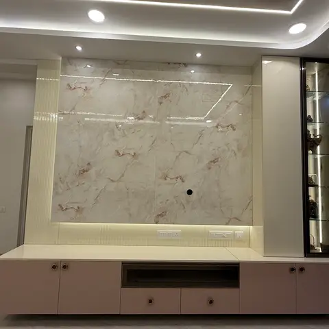Living room TV feature wall in book-matched cream and rust-veined marble with a fluted side pillar, a backlit blush-pink floating console below