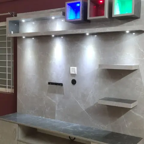 Living room TV feature wall in grey marble-effect panelling with a dark stone-top console and three RGB accent light boxes above, against a maroon wall.