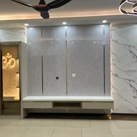 Living room TV feature wall in book-matched grey and white marble with brass inlay strips, a floating console