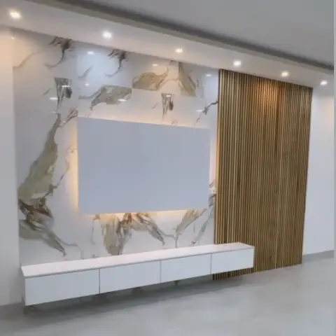 Living room TV feature wall with book-matched gold-veined marble cladding, a backlit blank display panel, a floating white TV console