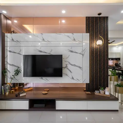 Living room TV feature wall with book-matched white marble cladding and dark fluted wood panelling, dining table visible behind