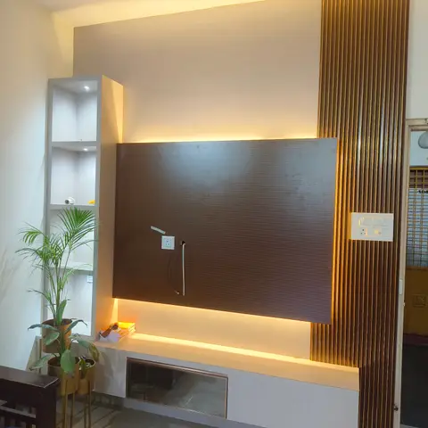 Living room TV feature wall with a textured brown panel backlit by a cove light strip, a gold fluted vertical trim column