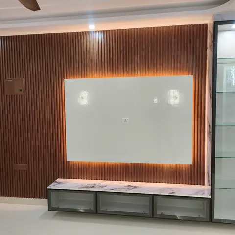 Living room TV feature wall with backlit fluted wood panelling, a marble-top floating media unit, and an adjoining glass display cabinet.