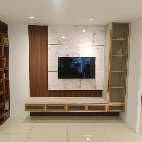 Living room TV feature wall with a large marble-look panel behind the mounted TV, a fluted wood panelling strip, a gold-trimmed glass-front floating console
