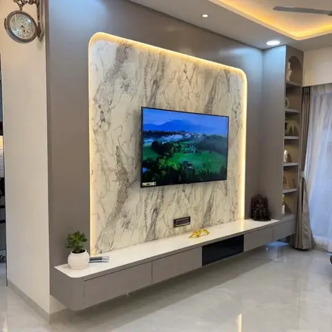 Living room TV feature wall with backlit book-matched marble cladding, a cove-lit ceiling, and a floating grey console below.