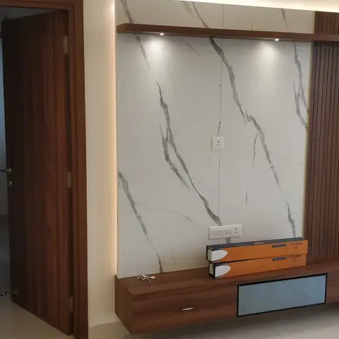 Living room TV feature wall with a large white-and-grey marble slab panel bordered by vertical fluted wood cladding and recessed spotlights