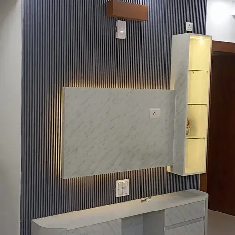 Living room TV feature wall with dark fluted panelling, a marble-finish floating TV console with rounded corners, and a backlit glass display cabinet.