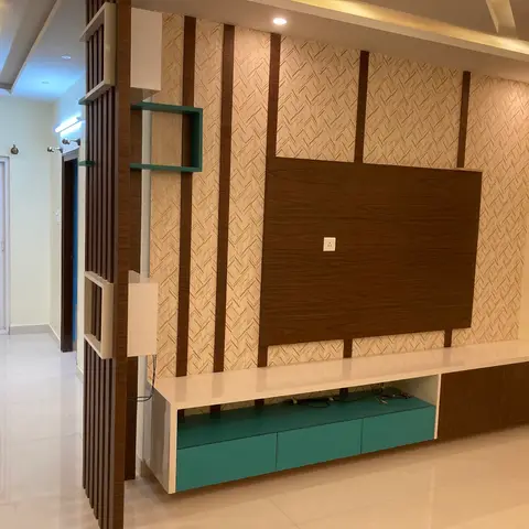 Living room TV feature wall with fluted wood panelling, herringbone-textured wallpaper, and a teal-and-walnut TV console beside a fluted slat room divider.