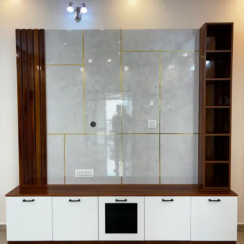 Living room TV feature wall with a grey marble-effect panel inlaid with brass strips, a fluted wood accent column, and a white base cabinet run.