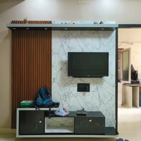 Living room TV feature wall with a white-marble-effect panel, fluted wood accent strip, and a black marble-effect floating console.