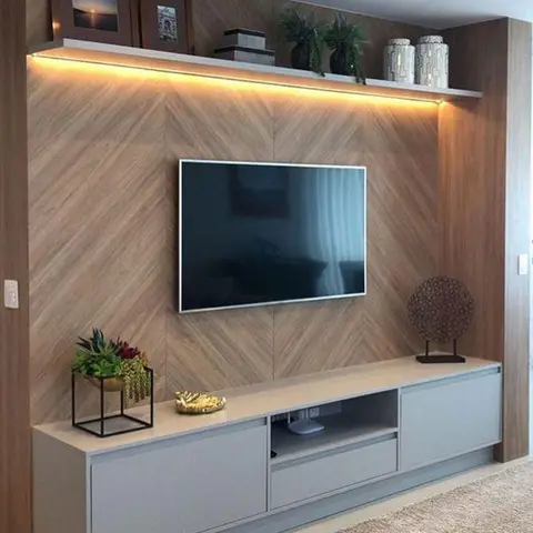Living room TV feature wall with herringbone wood panelling, a floating cove-lit display shelf styled with framed photos and plants