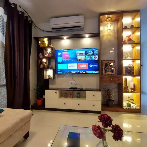 Living room TV unit in dark wood with backlit display niches holding teddy bears and showpieces, a marble-inset shelving column