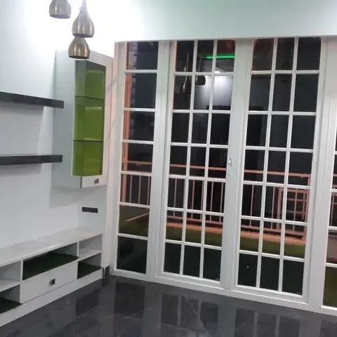 Living room TV unit wall in white gloss with green glass display shelving, next to a white-grille multi-panel glass door opening to a balcony