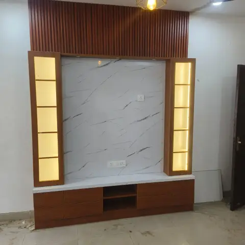 Living room TV unit wall with fluted wood panelling above, a marble-clad backdrop, backlit open display towers, and a wire-cage pendant light.