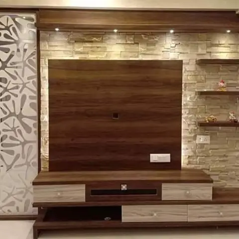 Living room TV unit wall with stacked stone cladding, spotlighting above a wood-panel TV backdrop with floating display shelves