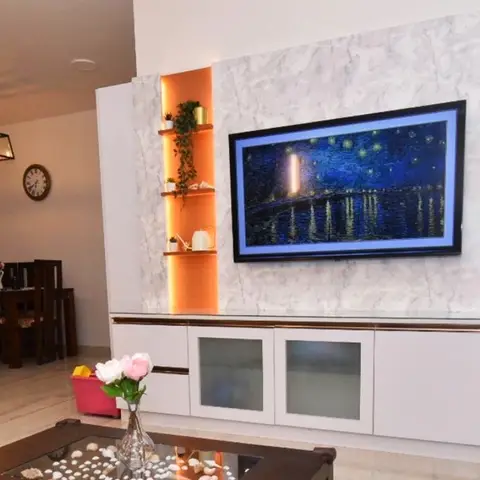 Living room TV unit with a grey marble-look feature panel, an orange-lit open display niche and a wall-mounted screen