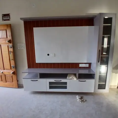 Living room TV unit with a fluted reddish-wood accent panel, matching tall glass-front display cabinet, and a wall-mounted white console with drawers