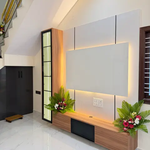 Living room TV wall built into the space under a staircase, with backlit grey panelling, a floating walnut TV console, a tall glass display cabinet