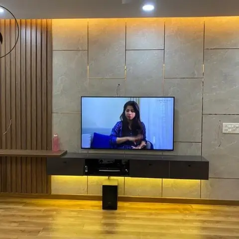 Living room TV wall clad in book-matched grey marble tiles with brass inlay strips, a backlit floating TV console, and a fluted wood accent panel beside it.