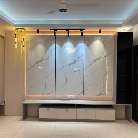 Living room TV wall clad in book-matched marble slabs with cove lighting and track spotlights, flanked by a fluted panel wall