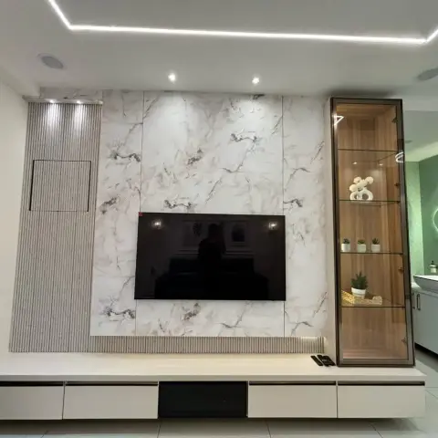 Living room TV wall clad in book-matched white marble with a fluted side panel and a backlit glass display cabinet, floating console below