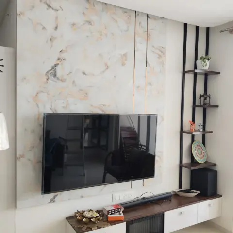 Living room TV wall clad in gold-veined marble with a floating wood-top TV unit below and a black ladder shelf styled with decor in the corner.