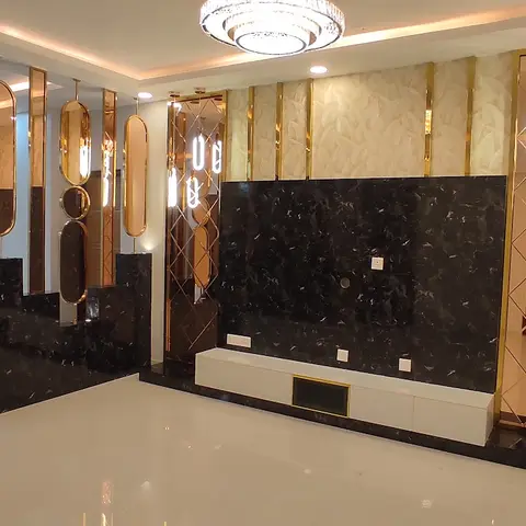 Living room TV wall clad in black marble with brass-trimmed mirror panels, a floating white-and-gold console