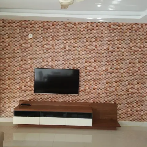 Living room TV wall clad wall-to-wall in small rust-and-beige split-face stone mosaic, with a low walnut-and-white console on an extended timber plinth