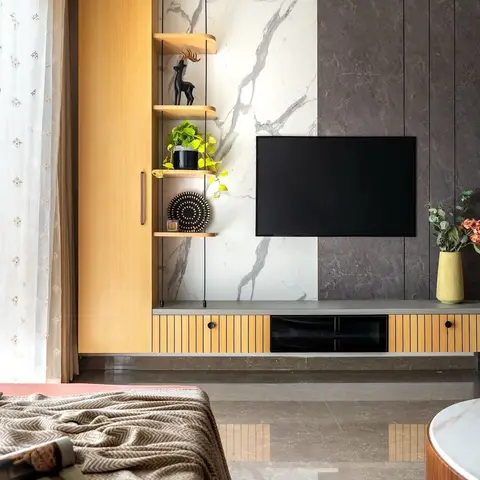 Living room TV wall combining bookmatched white marble and dark stone panels, a fluted oak media console