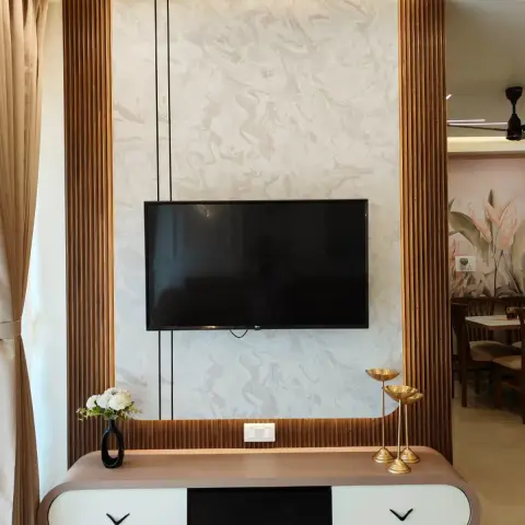 Living room TV wall framed in fluted wood-and-brass panelling around a marble-effect feature wall