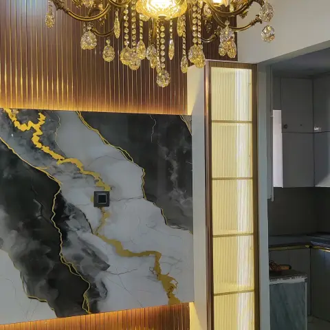 Living room TV wall in black-and-gold veined marble flanked by brass fluted panelling, lit by an ornate crystal chandelier