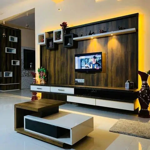 Living room TV wall in dark wood-veneer panelling with warm cove backlighting, floating cube display shelves styled with curios and brass vases
