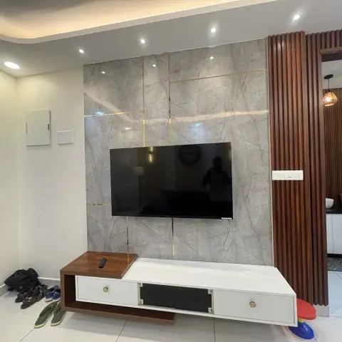 Living room TV wall in grey marble-look tile with brass inlay lines, a floating wood-and-white TV console