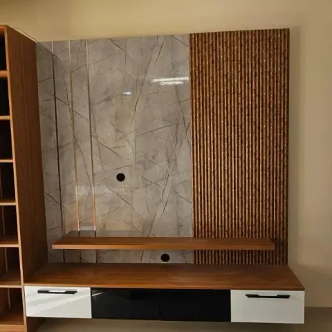 Living room TV wall in grey-veined marble with a vertical fluted-wood accent strip, over a floating wood-and-white TV console with black glass shutters.
