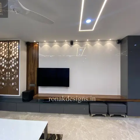 Living room TV wall in high-gloss white panelling beside a backlit carved wooden jaali screen and a walnut floating console