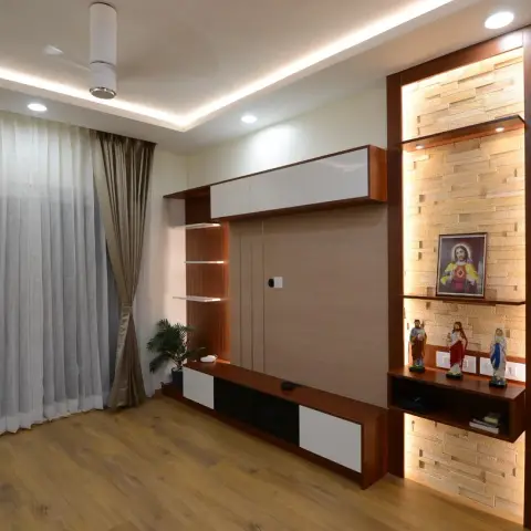 Living room TV wall in red-toned teak veneer with white gloss shutters, set beside a grazing-lit ledger-stone niche that holds a framed Sacred Heart picture