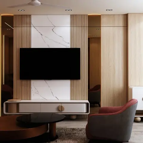 Living room TV wall in vertical wood fluting flanking a marble slab insert, with mid-century armchairs and a round wood coffee table.