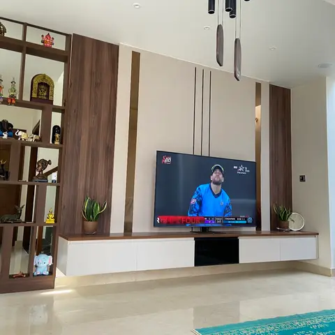 Living room TV wall in walnut panelling with a floating white console, flanked by an open wood curio shelf displaying brass and terracotta figurines.