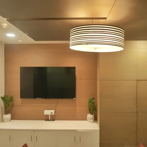 Living room TV wall in warm wood-veneer panelling with a white floating console and two potted plants