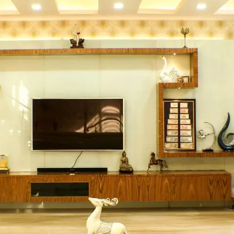 Living room TV wall in wood-veneer joinery with a backlit glass backdrop, densely styled with curio figurines, a framed currency note display