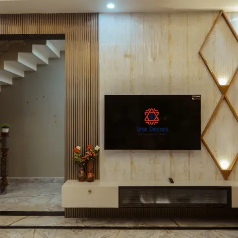 Living-room TV wall of gold-veined marble slab carrying a brass diamond lattice lit from inside its frames, flanked by full-height fluted wood panels