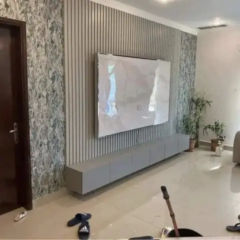 Living room TV wall pairing a grey fluted panel centerpiece with a botanical-print wallpaper border above a floating grey TV console.