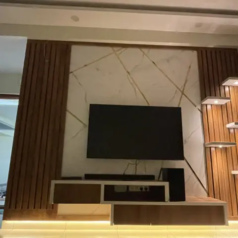 Living-room TV wall shortly before handover: teak fluted panels flank a white-and-gold veined marble slab