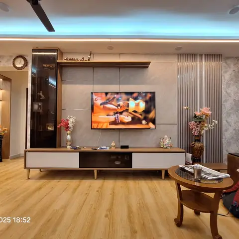 Living room TV wall unit in wood and white with a glass display cabinet, marble-look panel backdrop, fluted wall panelling