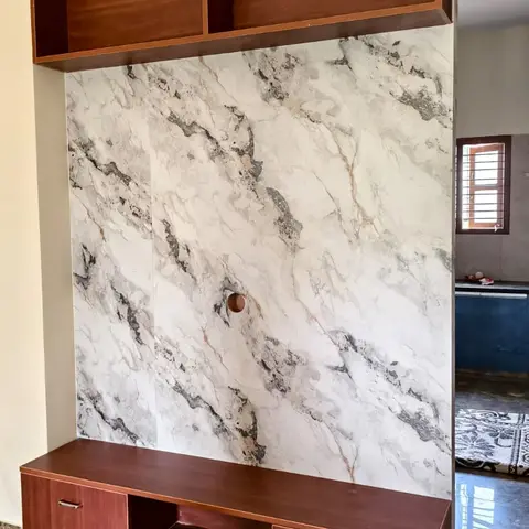 Living room TV wall with a bookmatched marble-effect stone slab backsplash between an open wood display shelf and a floating TV console.