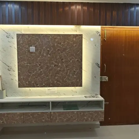 Living room TV wall with a backlit marble feature panel, dark wood fluted pelmet, and a floating marble-laminate console beside the main door.