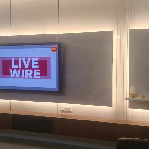 Living room TV wall with a backlit book-matched stone panel, fluted wood side panelling, a floating dark-wood console