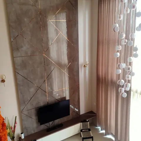 Living room TV wall with a copper-inlaid geometric marble panel and a cascading bubble-cluster pendant beside the window