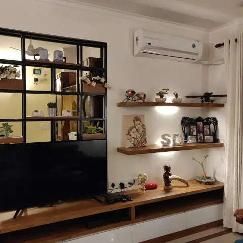 Living room TV wall with a floating wood-and-white console below open shelves styled with framed family photos and plants